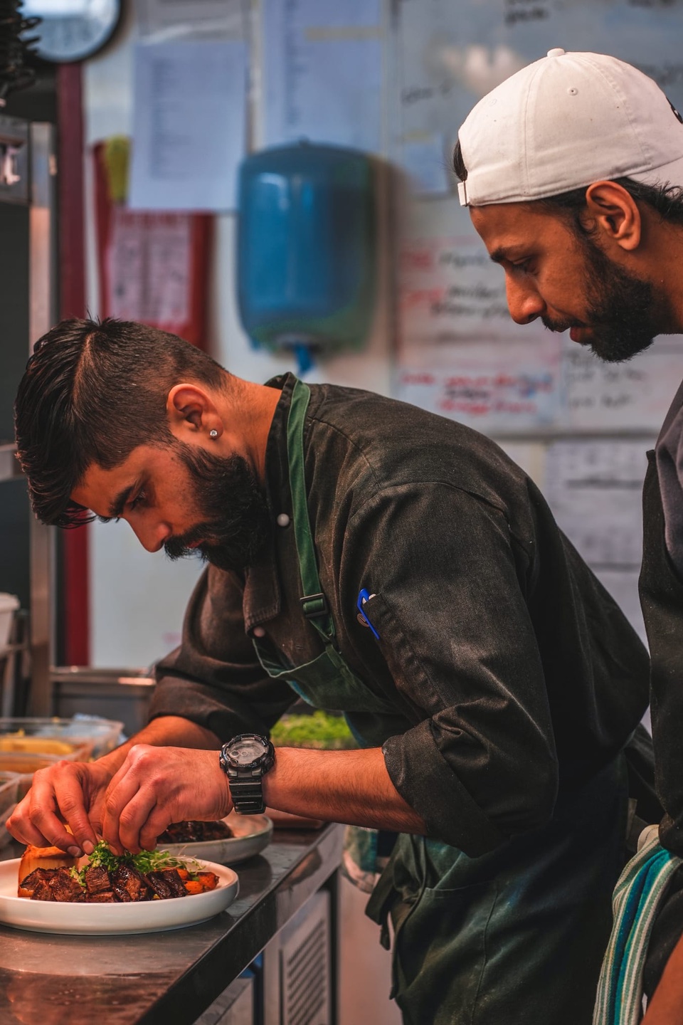 One chef putting together a dish while another watches