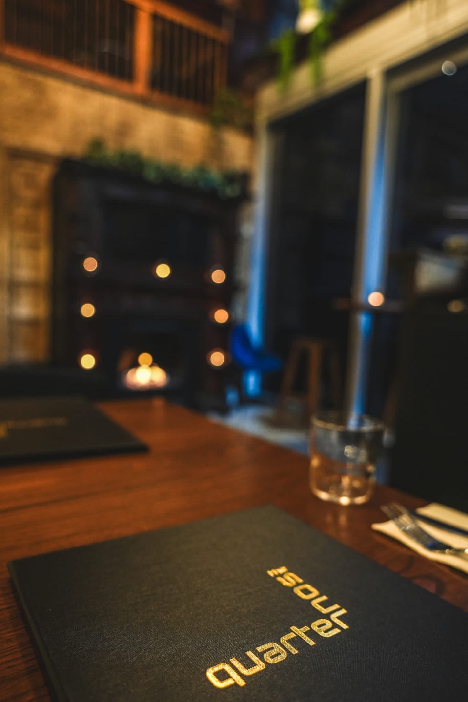A Soul Quarter menu at a set table with a fireplace in the background and tea light candles
